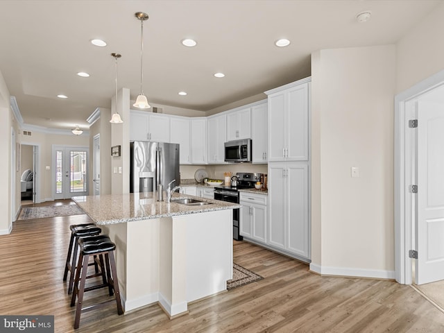 kitchen featuring stainless steel appliances, white cabinetry, a breakfast bar area, and an island with sink