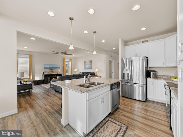 kitchen featuring white cabinets, sink, light wood-type flooring, an island with sink, and appliances with stainless steel finishes