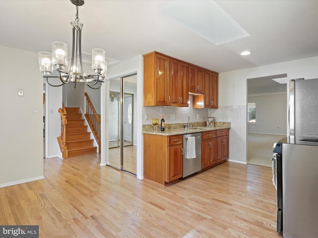 kitchen with sink, pendant lighting, light wood-type flooring, and appliances with stainless steel finishes