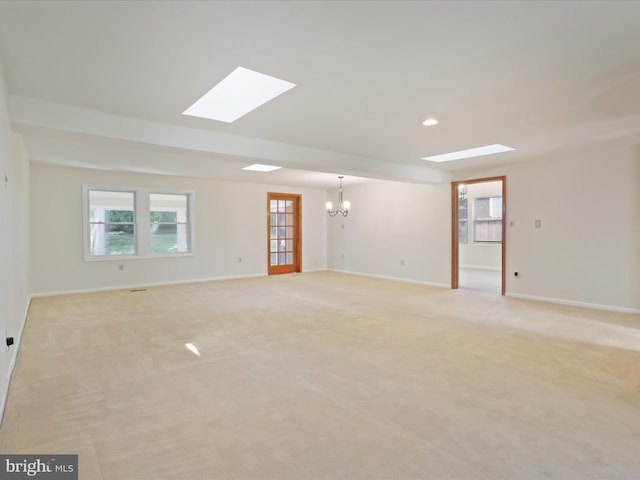 unfurnished room featuring a chandelier, light colored carpet, and a skylight