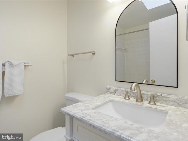 bathroom with vanity, a skylight, and toilet