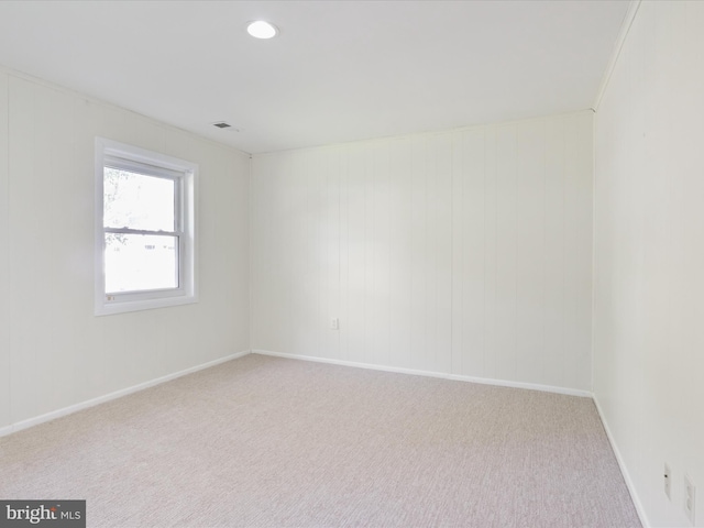 empty room with ornamental molding and light carpet