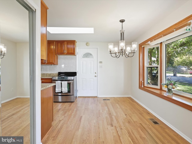 kitchen with backsplash, light wood-type flooring, stainless steel range with electric stovetop, and an inviting chandelier