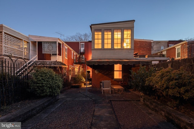 back house at dusk featuring a patio