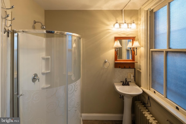 bathroom featuring tile patterned floors, a shower with door, and radiator