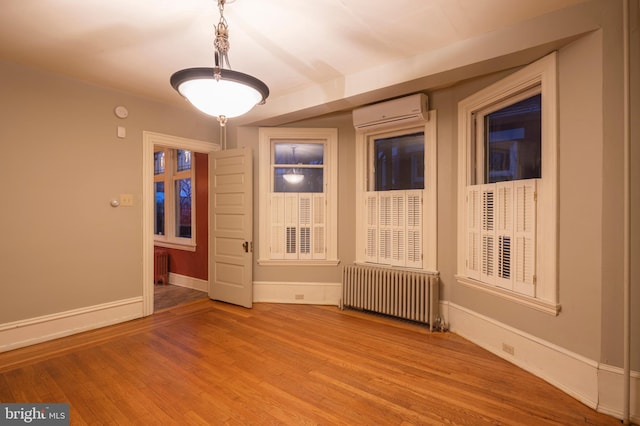 empty room featuring radiator heating unit, an AC wall unit, and light hardwood / wood-style flooring