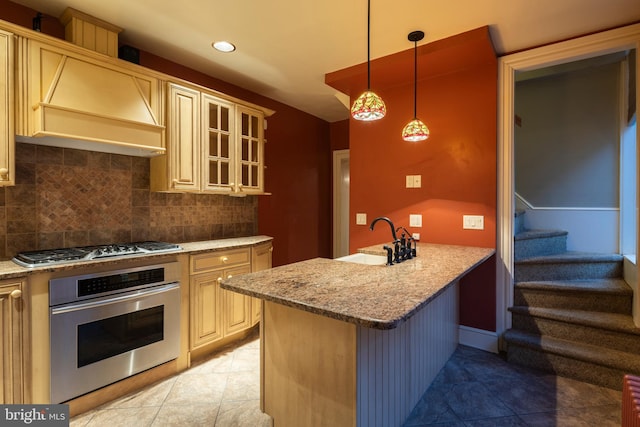 kitchen with decorative backsplash, premium range hood, a breakfast bar, stainless steel appliances, and sink