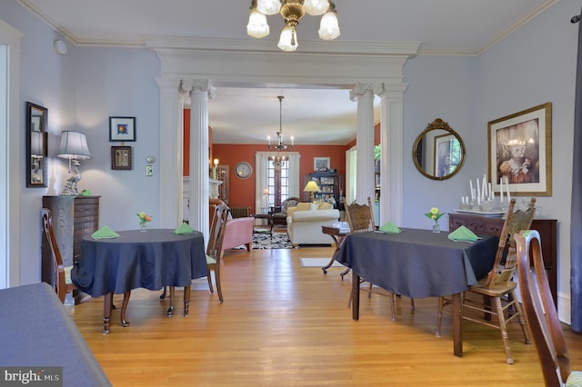 dining room with ornate columns, light hardwood / wood-style floors, and an inviting chandelier