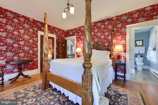 bedroom featuring dark hardwood / wood-style floors, ensuite bath, and a notable chandelier