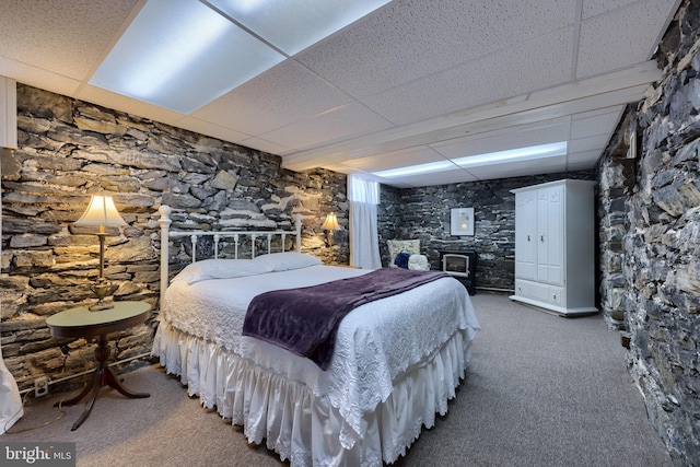 bedroom with a paneled ceiling, carpet floors, and a wood stove