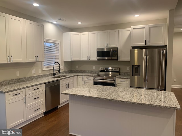 kitchen with dark wood-type flooring, sink, a kitchen island, white cabinetry, and stainless steel appliances