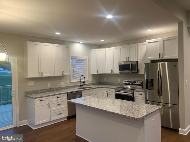 kitchen featuring white cabinets, a center island, light stone countertops, and appliances with stainless steel finishes