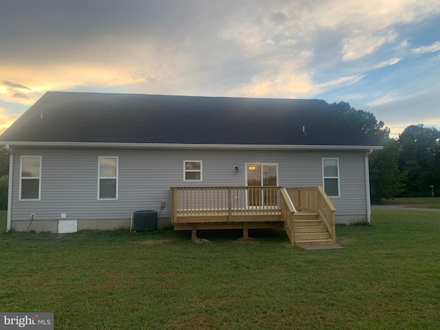 back house at dusk with a yard, a deck, and central AC unit