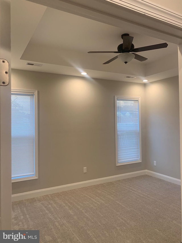 spare room featuring carpet flooring, a raised ceiling, and ceiling fan