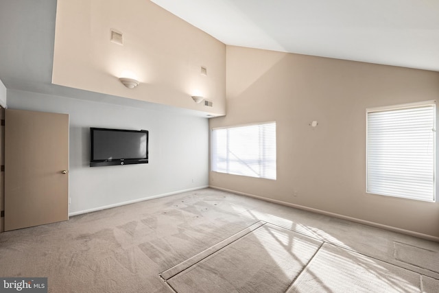 unfurnished living room with high vaulted ceiling and light colored carpet