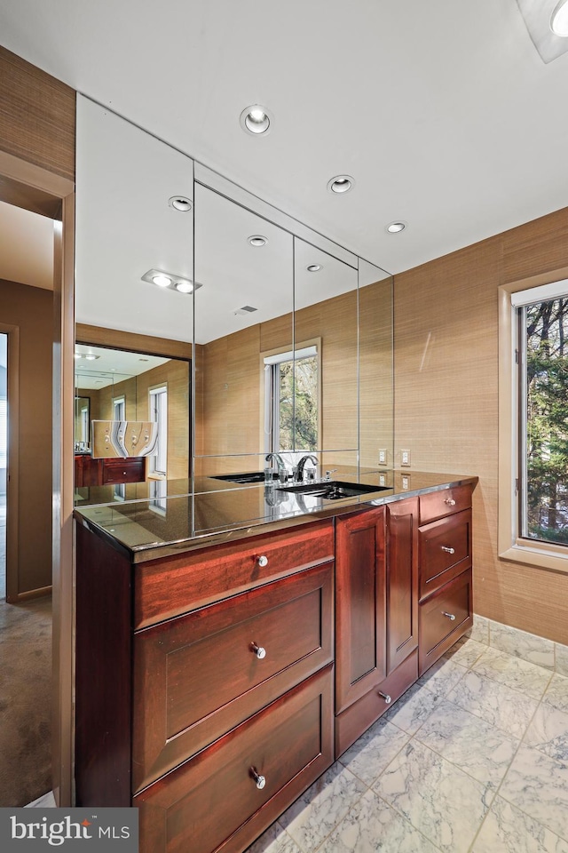 kitchen with a healthy amount of sunlight, hanging light fixtures, and dark stone countertops