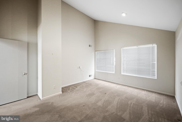 empty room with vaulted ceiling and light colored carpet