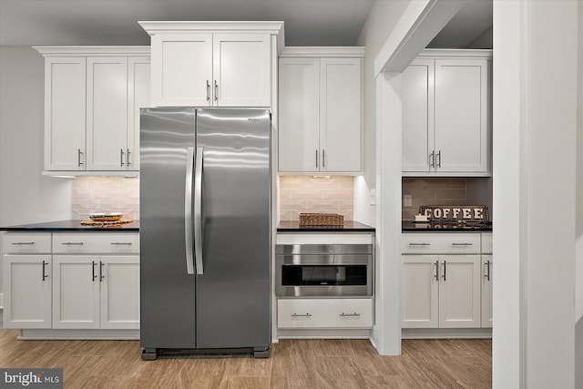 kitchen with appliances with stainless steel finishes, decorative backsplash, light hardwood / wood-style floors, and white cabinets