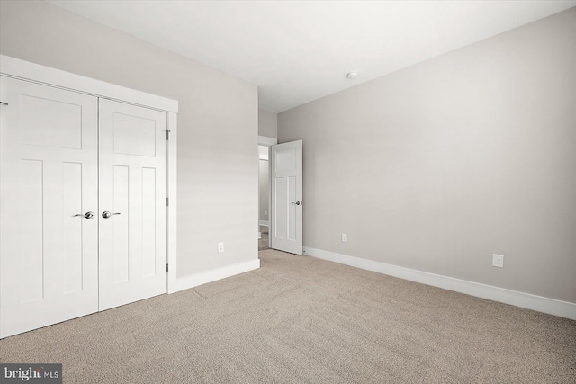 unfurnished bedroom with light carpet and a closet