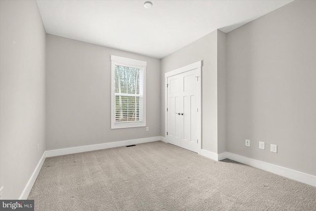 unfurnished bedroom featuring a closet and light colored carpet