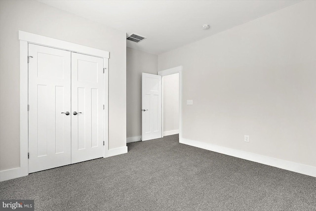 unfurnished bedroom with dark colored carpet and a closet