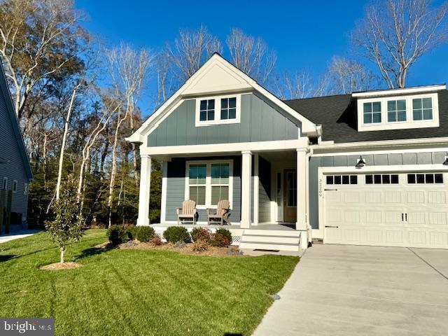 view of front of home with a front yard, covered porch, and a garage