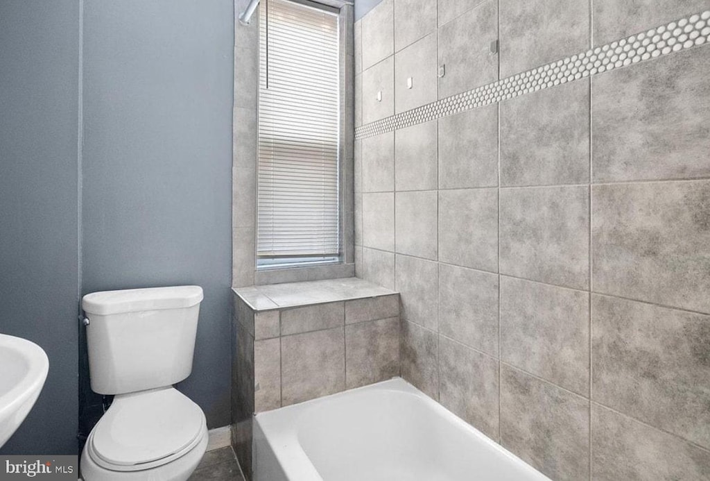 bathroom featuring sink, a washtub, and toilet