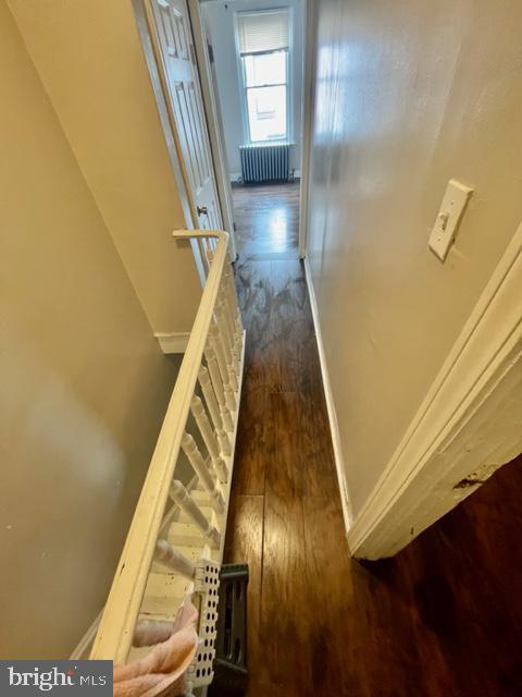 corridor with dark hardwood / wood-style flooring and radiator