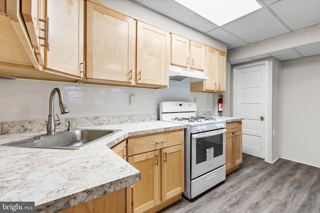 kitchen with a paneled ceiling, gas range oven, sink, light brown cabinets, and hardwood / wood-style flooring