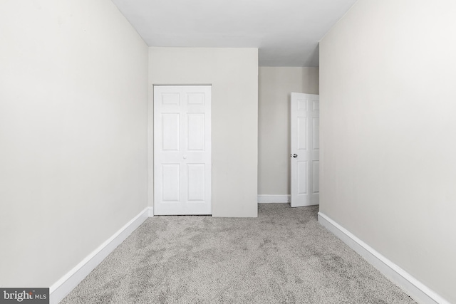 unfurnished bedroom with light carpet and a closet