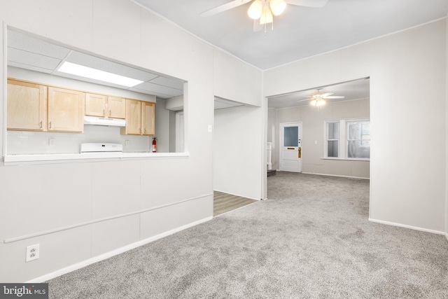 interior space with kitchen peninsula, light brown cabinetry, stove, and light colored carpet