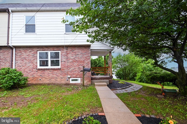 view of home's exterior featuring brick siding, a lawn, and a porch