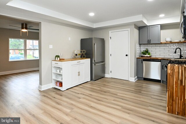 kitchen with appliances with stainless steel finishes, wooden counters, open shelves, light wood-style floors, and recessed lighting