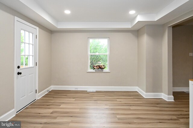 foyer with a raised ceiling, light wood-style flooring, baseboards, and recessed lighting