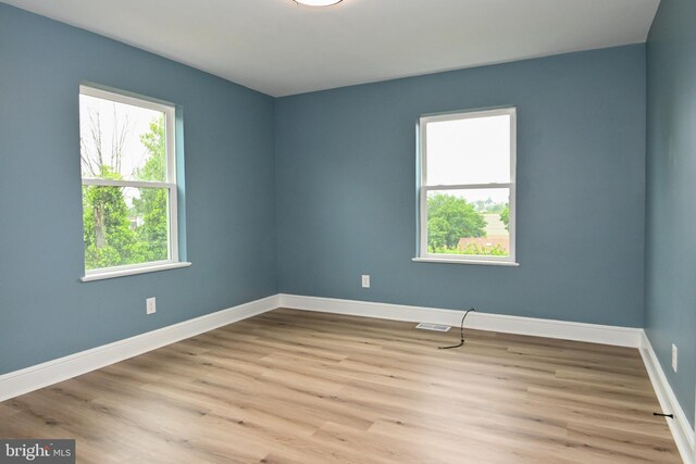 spare room with baseboards and wood finished floors