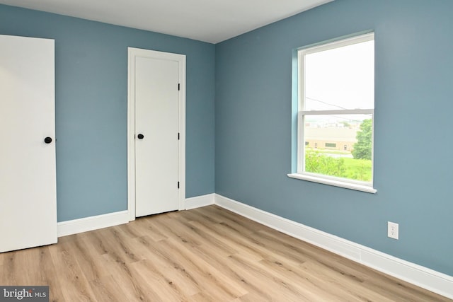 unfurnished bedroom with wood finished floors, baseboards, and a closet