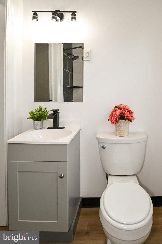 bathroom featuring baseboards, wood finished floors, vanity, and toilet