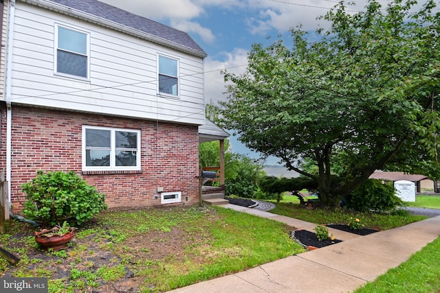view of property exterior featuring brick siding, a lawn, and a porch