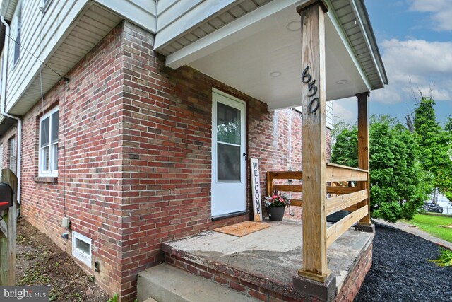 property entrance with covered porch and brick siding