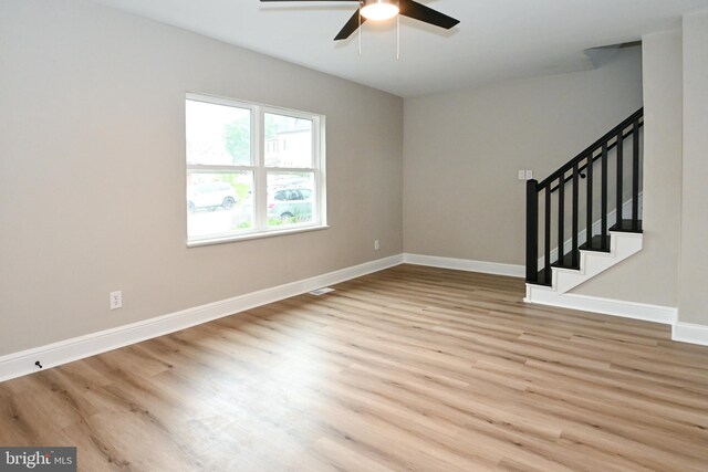 unfurnished room with ceiling fan, baseboards, wood finished floors, and stairs