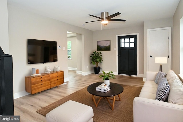 living area with light wood finished floors, baseboards, and a ceiling fan