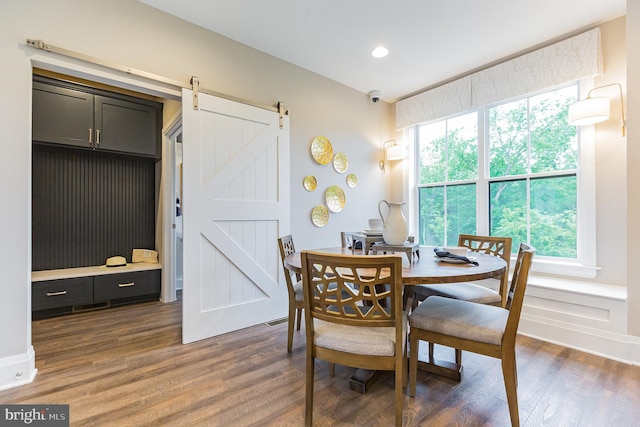 dining room featuring a barn door, a wealth of natural light, and dark wood-type flooring