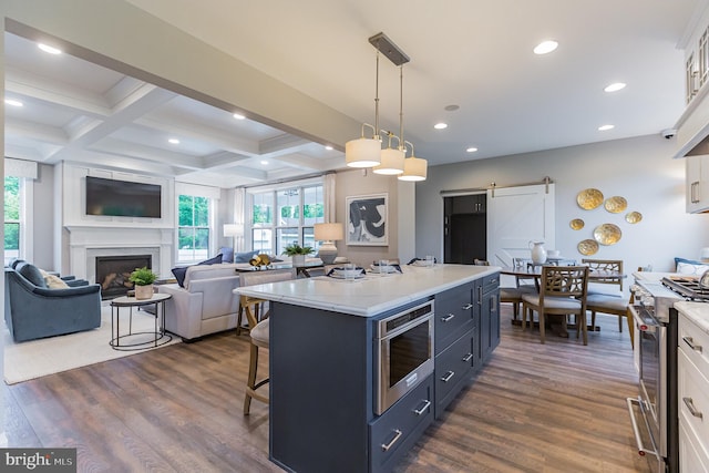 kitchen featuring a barn door, white cabinetry, hanging light fixtures, and stainless steel appliances