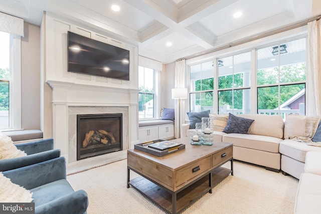 living room with beamed ceiling, ornamental molding, a high end fireplace, and coffered ceiling