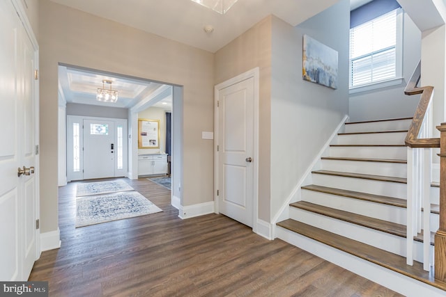 entrance foyer featuring dark hardwood / wood-style flooring, plenty of natural light, and a notable chandelier