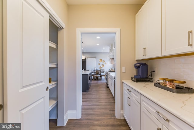 kitchen featuring tasteful backsplash, light stone counters, white cabinets, and dark wood-type flooring