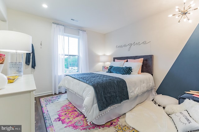 bedroom with hardwood / wood-style floors and an inviting chandelier