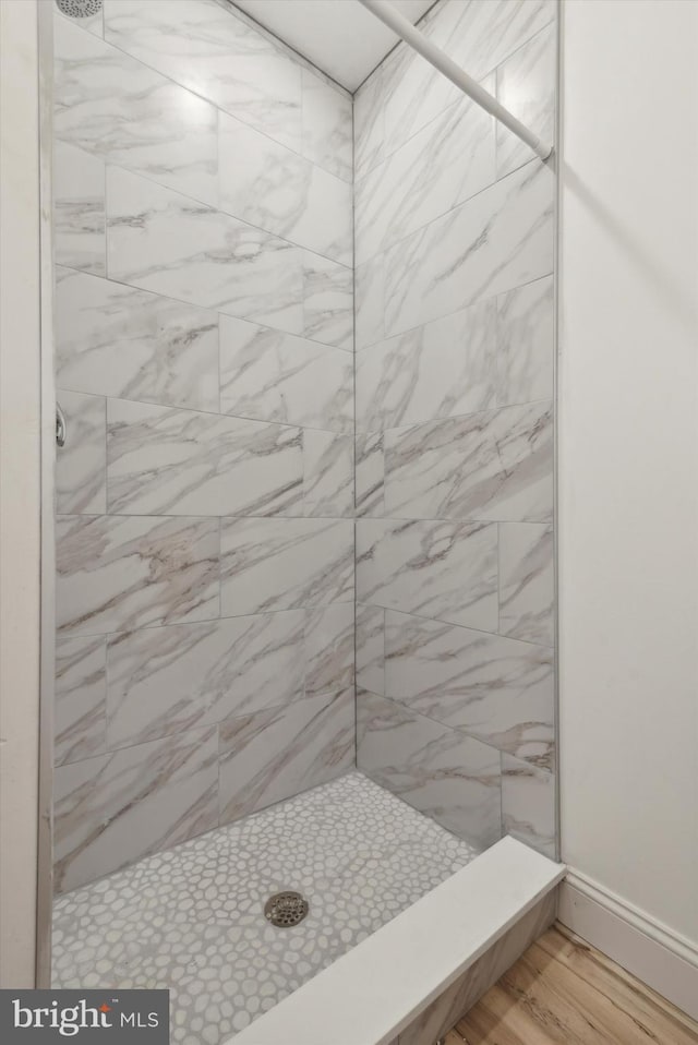 bathroom with hardwood / wood-style flooring and a tile shower