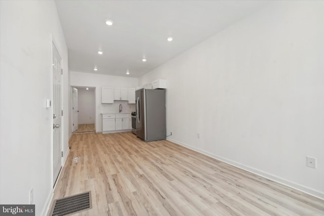 kitchen with light wood-type flooring, white cabinetry, and stainless steel appliances