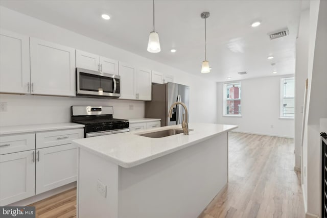 kitchen featuring white cabinetry, sink, hanging light fixtures, a center island with sink, and appliances with stainless steel finishes